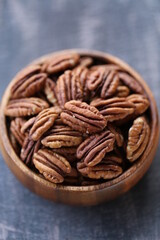 Pecan nut close-up in a round wooden cup on a black shabby board on wooden table background.Nuts and seeds. .Healthy fats.Heap shelled Pecans nut closeup.