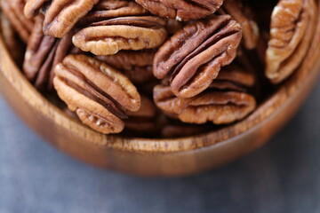 Pecan nut close-up in a round wooden cup on a black shabby board .Nuts and seeds. .Healthy fats.Heap shelled Pecans nut.keto diet.Tasty raw organic food snack