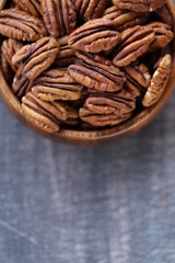 Pecan nut close-up in a round wooden cup on a black shabby board.Nuts and seeds. .Healthy fats.Heap shelled Pecans nut closeup.keto diet.Tasty raw organic food snack