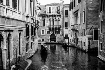 Venetian gondolier punting gondola through historical buildings of Venice Italy