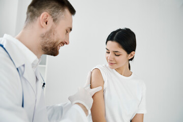 doctor with a stethoscope makes an injection into the shoulder of a woman patient covid vaccination