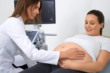 Gynecologist gently touching tummy of pregnant woman