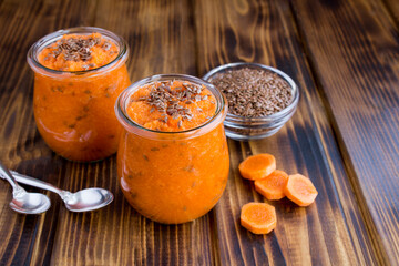 Carrot smoothies or puree with flax seeds in the glass jars on the wooden surface
