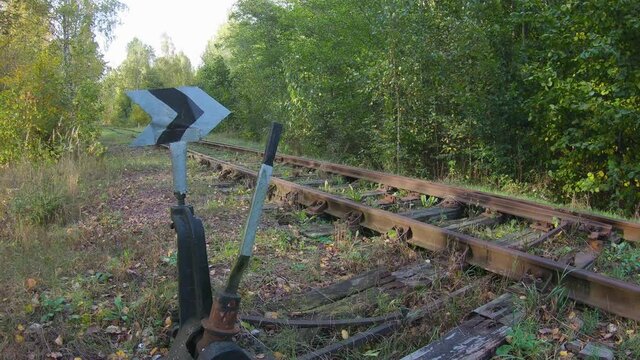 Manual railway switch with a pointer on a vintage rusty track in a wooded area. Concept of neglected infrastructure