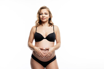 Smiling pregnant blonde woman in lingerie. Tenderness in anticipation of the baby. Space for text. White background.