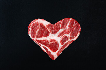 Fresh raw meat in the shape of heart on a black background