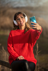 Mujer joven escuchando música con auriculares en parque.