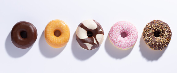 Flat lay composition with mixed donuts on white background.