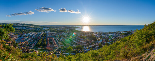 Panorama Sunset view from above of Huskvarna Skyline with reflecting sun on big Lake Vattern near Jonkoping, Smaland, Sweden.