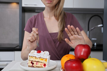 Woman choosing to eat cake instead of fruits. Sugar addiction , unhealthy lifestyle concept