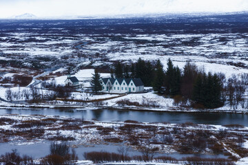 Selective focus - Landscape in Iceland with houses, mountains, rivers, trees and snow