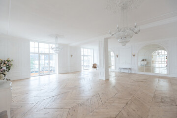 chic white huge spacious hall with a minimum of expensive antique furniture. Baroque interior design with ornament on the walls and parquet on the floor.