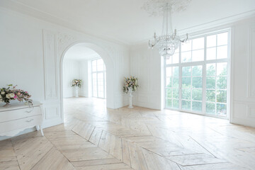 chic white huge spacious hall with a minimum of expensive antique furniture. Baroque interior design with ornament on the walls and parquet on the floor.