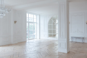 chic white huge spacious hall with a minimum of expensive antique furniture. Baroque interior design with ornament on the walls and parquet on the floor.