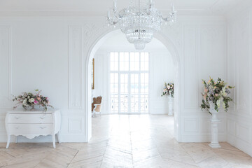 chic white huge spacious hall with a minimum of expensive antique furniture. Baroque interior design with ornament on the walls and parquet on the floor.