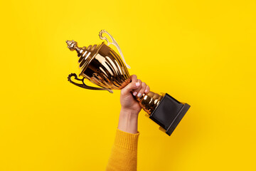 Hand of the person with a sports cup over yellow background - obrazy, fototapety, plakaty