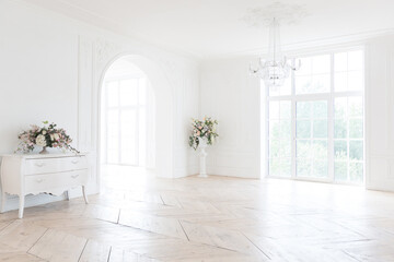 Fototapeta na wymiar chic white huge spacious hall with a minimum of expensive antique furniture. Baroque interior design with ornament on the walls and parquet on the floor.
