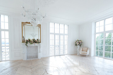 chic white huge spacious hall with a minimum of expensive antique furniture. Baroque interior design with ornament on the walls and parquet on the floor.