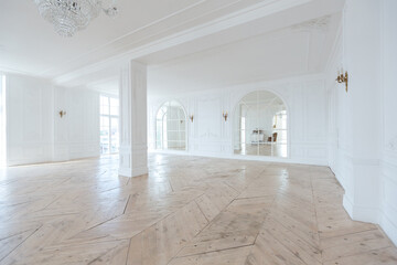 chic white huge spacious hall with a minimum of expensive antique furniture. Baroque interior design with ornament on the walls and parquet on the floor.