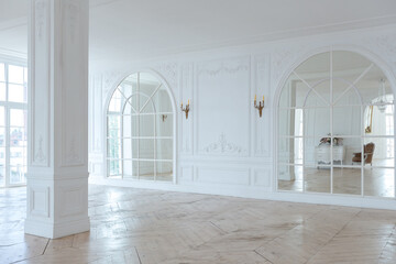 chic white huge spacious hall with a minimum of expensive antique furniture. Baroque interior design with ornament on the walls and parquet on the floor.