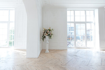 chic white huge spacious hall with a minimum of expensive antique furniture. Baroque interior design with ornament on the walls and parquet on the floor.