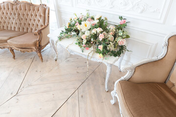 chic white huge spacious hall with a minimum of expensive antique furniture. Baroque interior design with ornament on the walls and parquet on the floor.