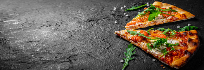 two slice of Pizza with Mozzarella cheese, salmon fish, tomato sauce, arugula. Italian pizza on Dark grey black slate background - obrazy, fototapety, plakaty