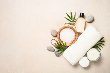 Fototapeta na wymiar Spa background. Cosmetic product, towel and sea salt at stone table. Top view image.