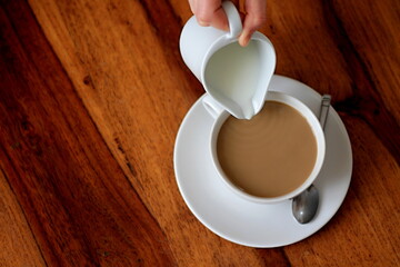 coffee on table with hand poring white milk stock photo
