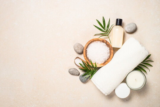 Spa background. Cosmetic product, towel and sea salt at stone table. Top view image.
