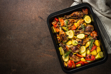 Baked chicken with vegetables preparing in the oven at baking sheet. Top view.