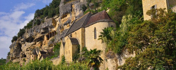 Fototapeta premium Panoramique église en pierres du village de La-Roque-Gageac (24250) dans son rocher, département de la Dordogne en région Nouvelle-Aquitaine, France