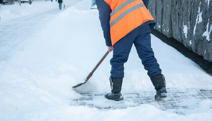 Workers remove snow from the sidewalks. Russian Winter. Snow removal.