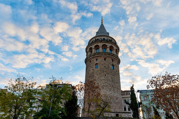 Fototapeta na wymiar View of Galata Tower from below surrounded by classic buildings against blue sky