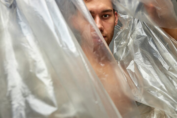 environmental protection, people and recyclable plastic concept, man wrapped in plastic bag,...
