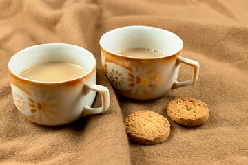 Two cups with coffee and two small cookies