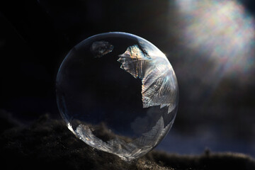 Frozen soap bubble with ice crystals at sunlight