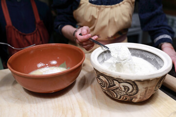 Woman adding flour to bowl for making dough