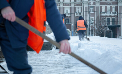 Workers remove snow from the sidewalks. Russian Winter. Snow removal.