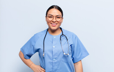 hispanic woman smiling happily with a hand on hip and confident, positive, proud and friendly...