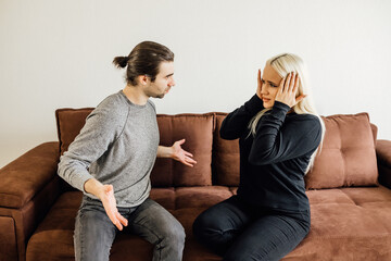 Angry man shouted at his wife, who covered her ears with her hands. family crisis conflict concept