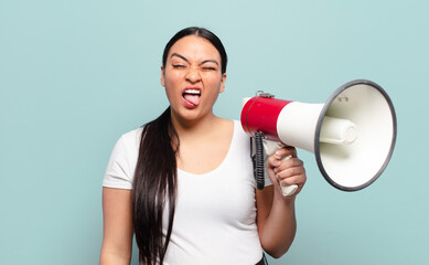 hispanic woman with cheerful, carefree, rebellious attitude, joking and sticking tongue out, having...