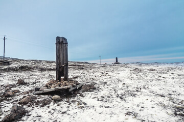 A broken telegraph pole on a snow-covered Arctic hill. Minimalistic polar landscape.