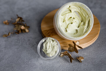 A jar of face cream on a wooden stand on a gray background. Set for skin and body care beauty products