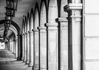 Perspective view of a corridor between columns and arch with lamps on the ceiling in a street in Granada (Spain)