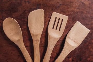 Overhead shot of bamboo kitchen utensils and shovels arranged in a half moon, on a wooden background.