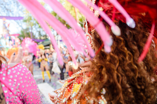 Dancers wearing colorful feathers costumes gathered for a parade. Back view blurry defocused unrecognisable crowd image great for graphic background.
