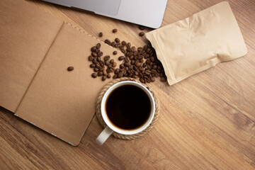 cup of coffee, coffee beans and notebook on wooden table in workplace, selective focus. For goals list background, top view. copy space for your text