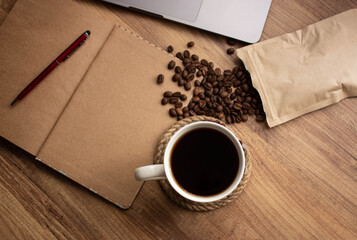 modern life and coffee lovers life. Selective focus coffee in mug on wooden table. Coffee, coffee beans, notebook, red pen for to do list or goals list background working lifestyle. copy space.	