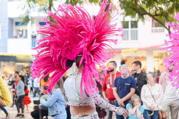 Dancers wearing colorful feathers costumes gathered for a parade. Back view blurry defocused...